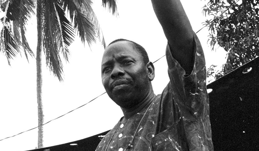 Ken Saro-Wiwa, le regard grave, lève le bras