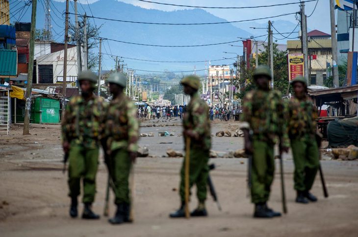 Au premier plan : des membre de la police anti-émeutes, armés et en uniformes militaires. En arrière-plan : des gens attroupés dans la rue. Kisume (Kenya) en 2017.