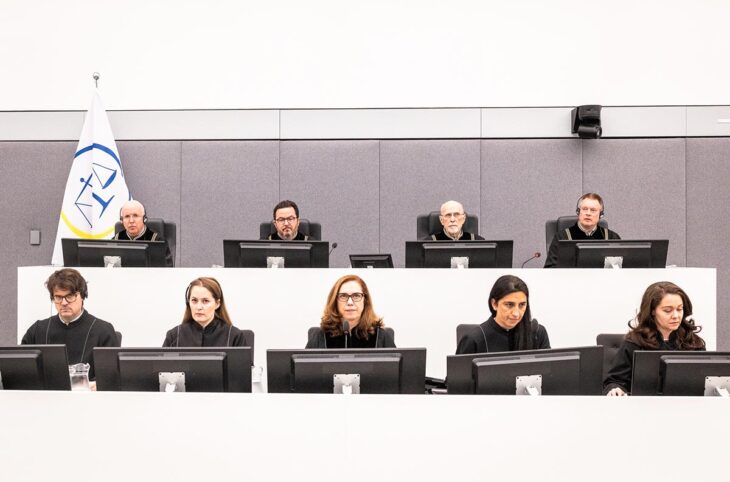 Les Chambres spécialisés du Kosovo (KSC), une cour internationale de l'Onu basée à la Haye (Pays-Bas), vient de juger 4 personnalités kosovares inculpées pour crimes de guerre, dont l'ex-président Hashim Thaçi. Photo : les 4 juges sont assis sur une estrade au-dessus de leurs 5 assistants dans un décor blanc très lumineux et froid.