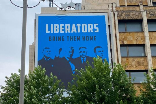 Les Chambres spécialisées du Kosovo (KSC) : un tribunal spécial (basés à La Haye) pour les crimes de guerre et crimes contre l'humanité commis par les forces kosovares durant la guerre contre la Serbie, dont l'objet et le fonctionnement sont controversés. Photo : une grande affiche bleue est accrochée à un immeuble. Il y est écrit : 