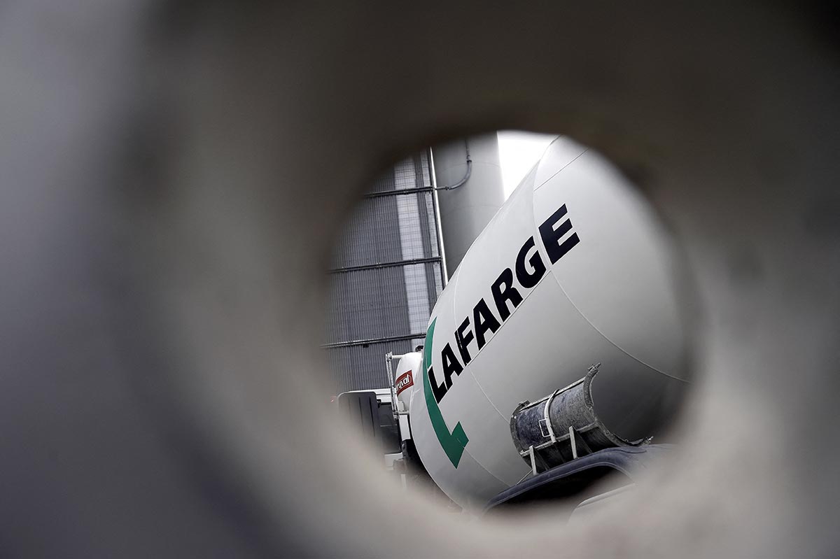 A concrete mixer (truck) displaying the logo of the French cement company Lafarge, is seen through a cement pipe