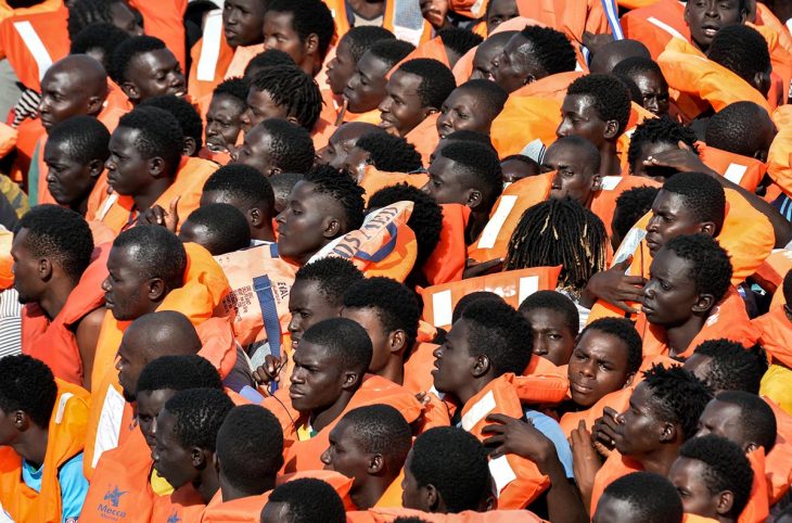 Many people wearing life jackets wait untel the are rescued from a rubber boat