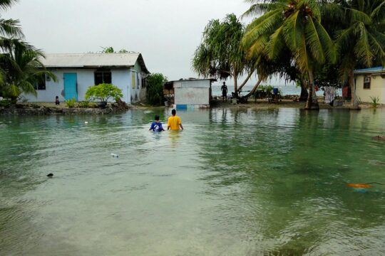 Climate change - Following a sudden rise in water levels, two residents of the Marshall Islands are walking with water up to their chests.