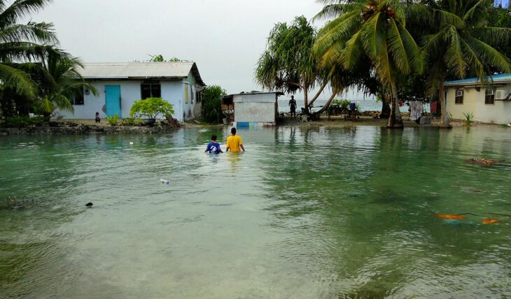 Changement climatique - Suite à une montée des eaux soudaines, deux habitants des Iles Marshall marchent avec de l'eau jusqu'à la poitrine.