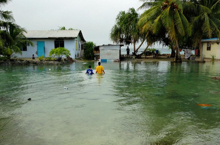 Changement climatique - Suite à une montée des eaux soudaines, deux habitants des Iles Marshall marchent avec de l'eau jusqu'à la poitrine.