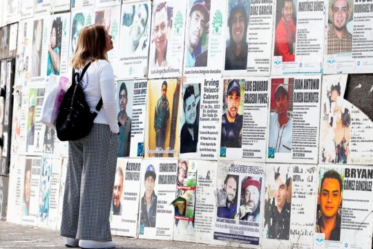 Enforced disappearances in Mexico: when the UN gets involved. Photo: a mother searches for her missing son, looking at posters of missing persons on a wall in the street.