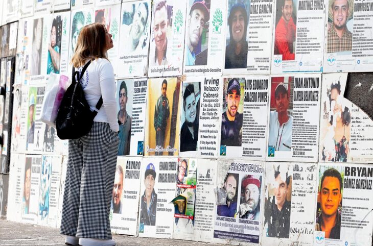 Disparitions forcées au Mexique : quand l'Onu s'en mêle. Photo : une mère recherche son fils disparu en observant des affiche de personnes disparues, sur un mur dans la rue.