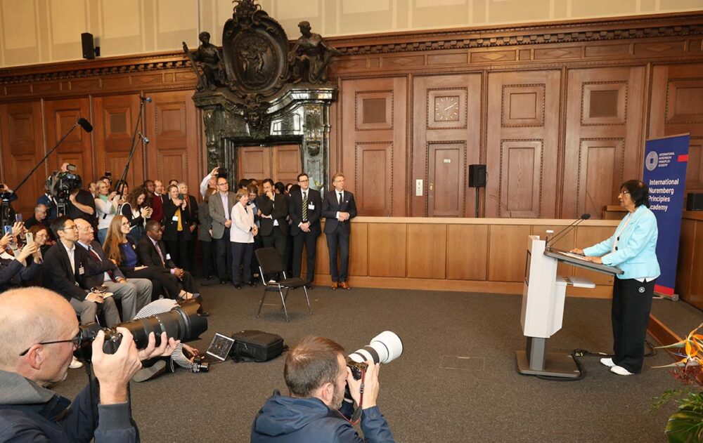 Après avoir reçu le prix Nobel de la paix, le 9 octobre 2026, la juriste sud-africaine Navanethem Pillay (à droite) s’adresse aux journalistes dans la salle d’audience historique n° 600 du Palais de justice de Nuremberg, où s’étaient tenus les procès des dirigeants de l’Allemagne nazie. Photo : © Frank Boxler / AFP Navi Pillay (juriste expérimentée et spécialisée en droit international) reçoit le prix Nobel de la Paix à Nuremberg. Photo : Pillay prononce un discours devant la presse dans le Palais de justice de Nuremberg.