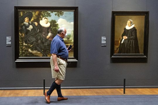 Un homme marche devant des oeuvres d'art exposées au Rijksmuseum d'Amsterdam (Pays-Bas)