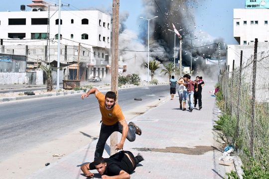 Palestinians try to escape debris blown up by the Israeli army's shelling of a home in Gaza