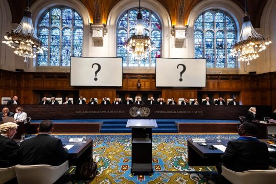 International Court of Justice (ICJ): 2 questions for peace in Palestine. Photo: view of the court during the hearing of South Africa (right) against Israel (left), facing the judges. 2 question marks are embedded in screens.