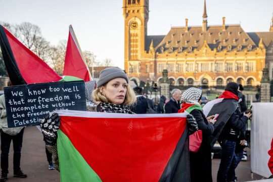 Is international justice relevant to prevent genocide in Gaza? Photo: A protestor holds a Palestinian flag in front of the International Court of Justice (ICJ), in The Hague.