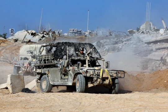 What justice for arms dealers and their complicity in the crimes committed in Gaza, including genocide? Photo: An Israeli armoured vehicle drives through a destroyed street in Gaza City.