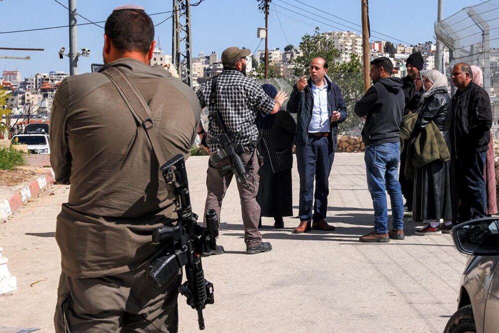 Why is the International Criminal Court (ICC) struggling to deal globally with the multiple international crimes perpetrated by Israel in Palestine (Gaza and the West Bank)? Photo: Armed Israeli settlers talk to Palestinians in Hebron.