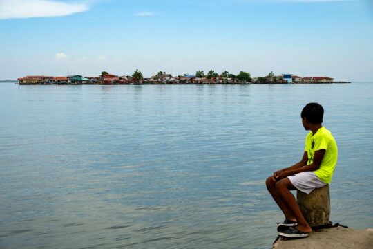 The International Court of Justice (ICJ) has just declared that climate change must be a priority for humanity and that states are legally responsible for it, to the extent that they must provide compensation for victims. Photo: a child looks at a tiny island dotted with houses in the distance, at almost the same level as the water surrounding it.