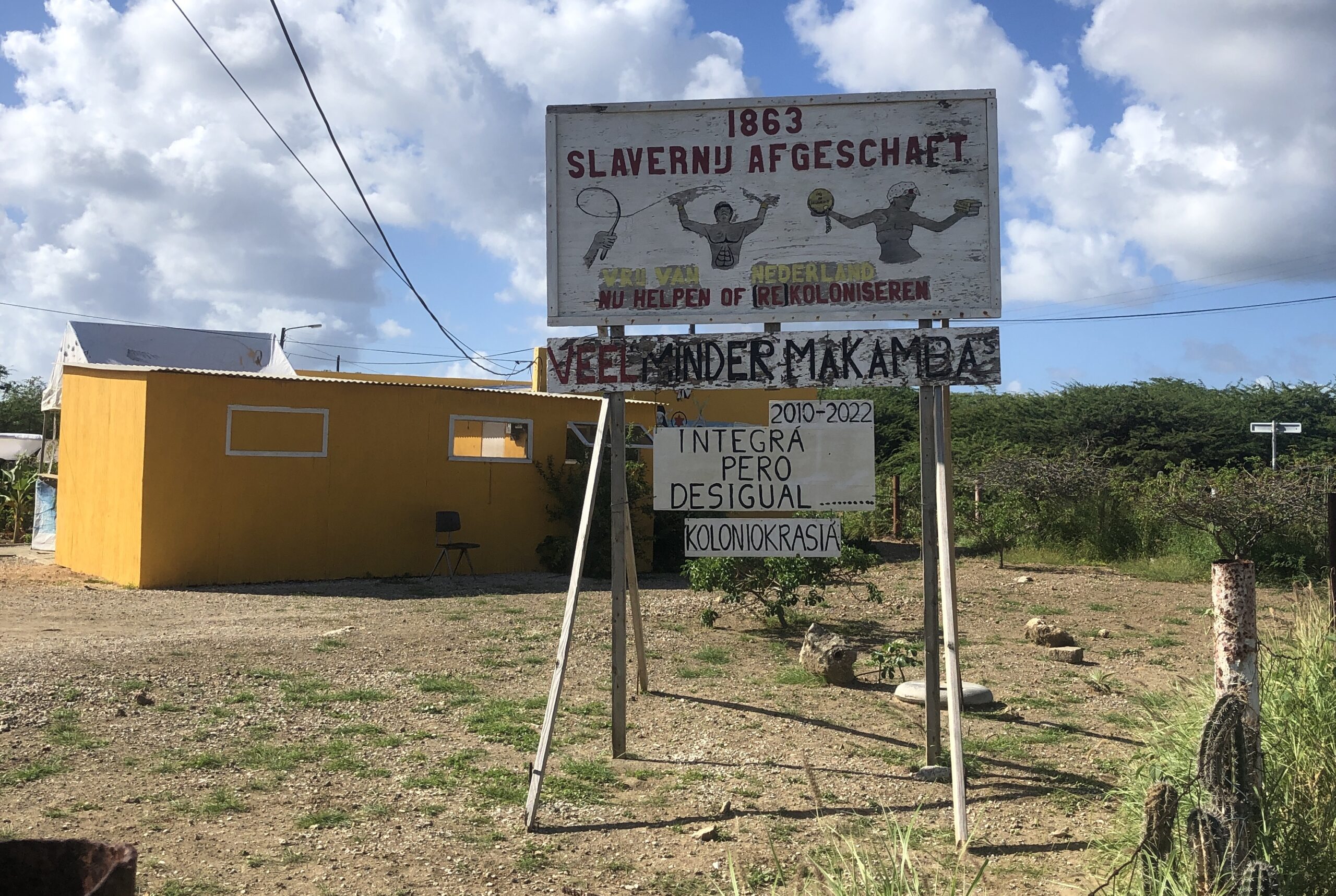 Un panneau avec l'inscription suivante : "1863, abolition de l'esclavage. Libérez-vous des Pays-Bas. Aidez maintenant ou (re)colonisez. Beaucoup moins de Makambas".