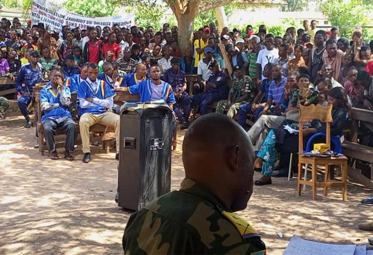 Audience foraine dans un village du Kasaï (RDC). Les 7 accusés du procès Kamuina Nsapu sont au centre, entourés de militaires et d'une foule de villageois.