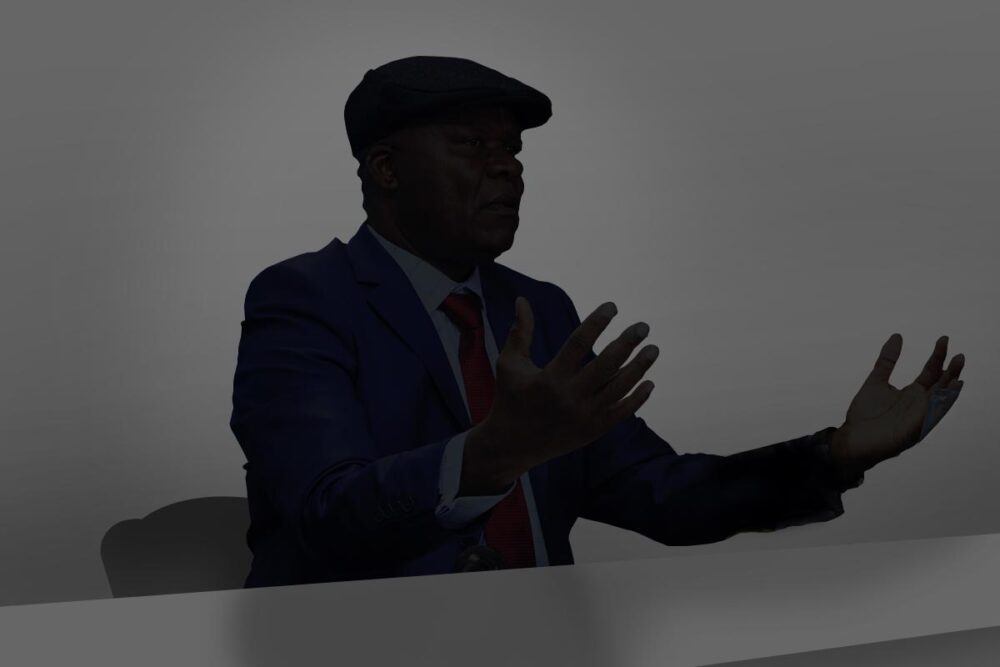 The trial of Roger Lumbala (DRC) in France and the principle of universal jurisdiction in international law. Image: Lumbala appears as a black silhouette against a grey background, sitting at a desk. He speaks with his hands raised and wears a beret.