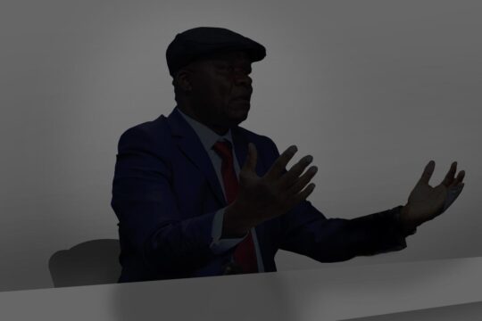The trial of Roger Lumbala (DRC) in France and the principle of universal jurisdiction in international law. Image: Lumbala appears as a black silhouette against a grey background, sitting at a desk. He speaks with his hands raised and wears a beret.