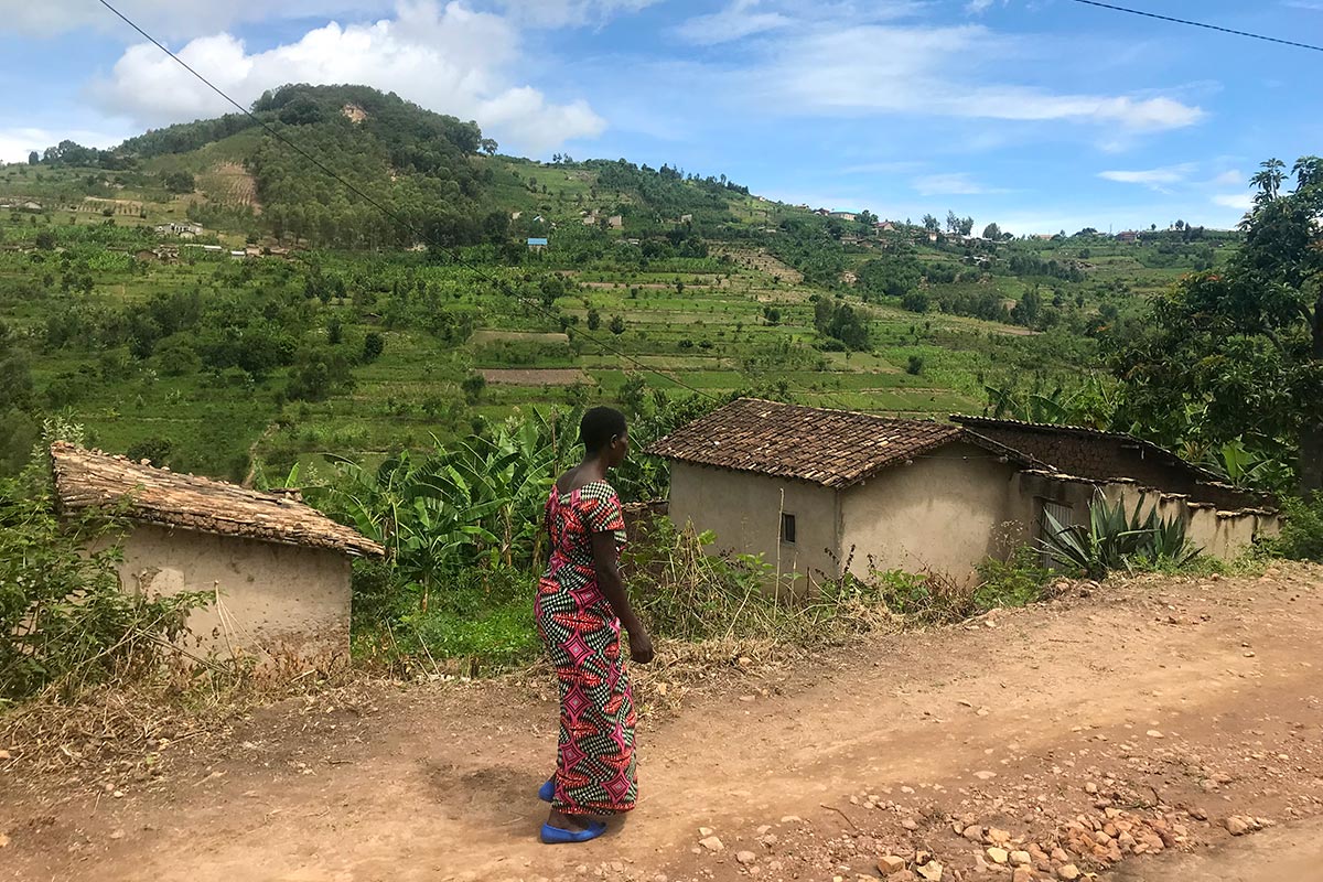 Le mont Mayunzwe au Rwanda, lieu emblématique du génocide de 1994. Photo : une femme marche sur le chemin en bas de la colline.