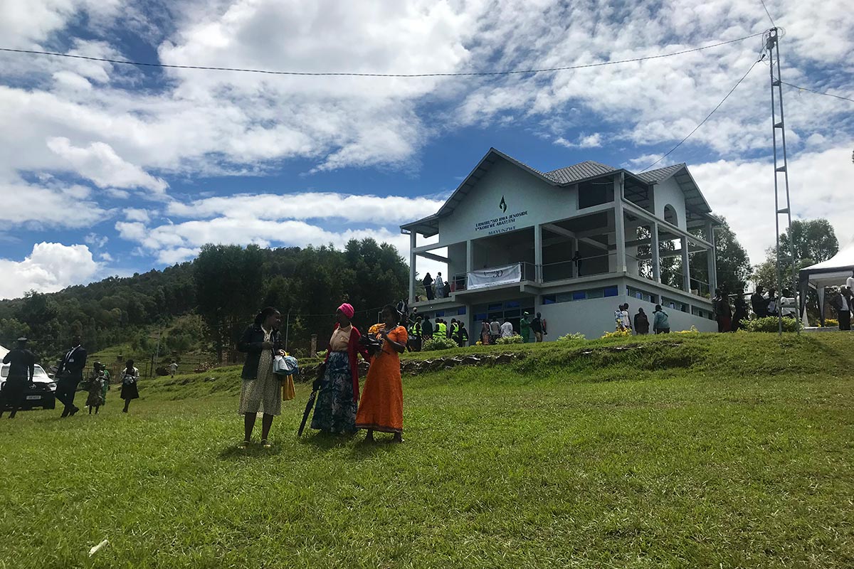 Le mémorial de Mayunzwe, au Rwanda, où de nombreuses victimes du génocide reposent. Photo : 3 femmes discutent et observent le panorama et les collines rwandaises en contrebas du bâtiment.