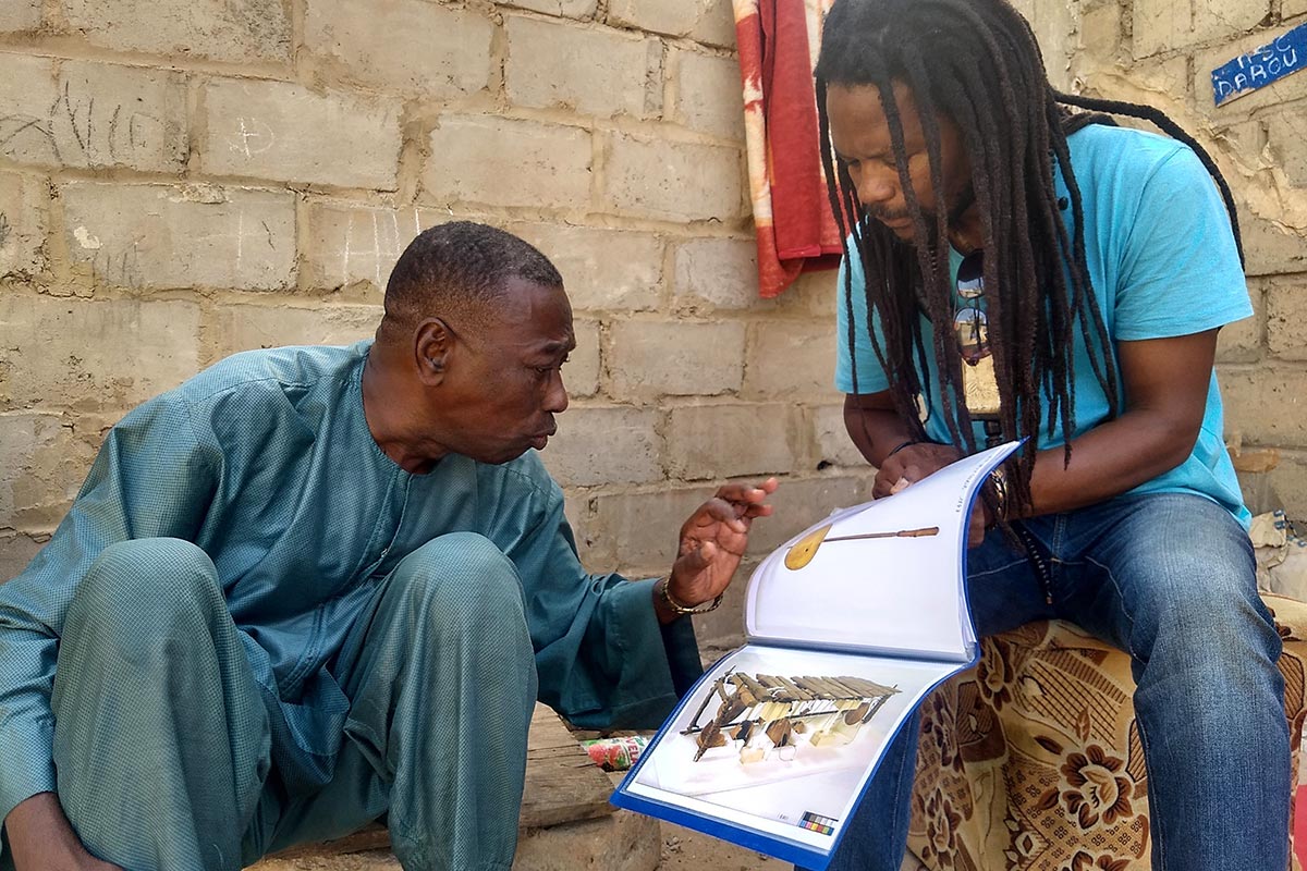 Harouna Daouda Dia observe une photographie que lui présente Issa Dia