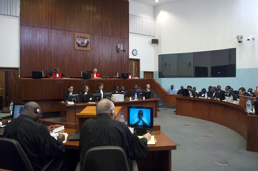 On the bench below the judges, legal assistants, court clerks, and bailiffs listen to a witness testifying before the Special Court for Sierra Leone.