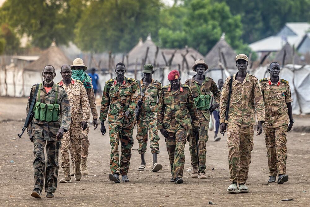 Members of the South Sudan People’s Liberation Army in Opposition (SPLA-IO) in the strategic opposition-controlled town of Akobo, in the Jonglei State, where the current violence is particularly bad, according to the UN, on February 12, 2026. Photo: © Luis Tato / AFP In South Sudan, a civil war is on the verge of engulfing the country as transitional justice processes stall. Photo: a group of soldiers in mismatched uniforms (only a few of whom are armed) from the Sudan People’s Liberation Army marching in unsuitable footwear.