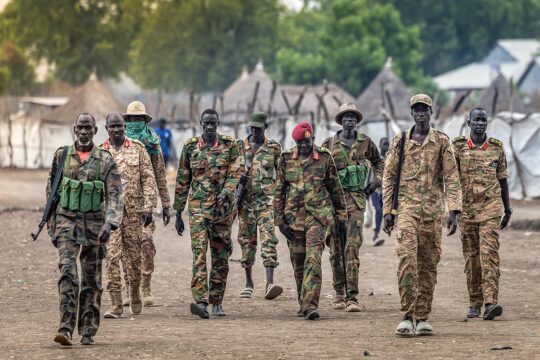 In South Sudan, a civil war is on the verge of engulfing the country as transitional justice processes stall. Photo: a group of soldiers in mismatched uniforms (only a few of whom are armed) from the Sudan People’s Liberation Army marching in unsuitable footwear.