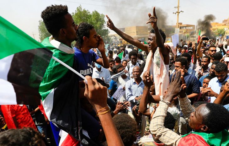 Sudanese protesters march in Khartoum, waving flags of Sudan