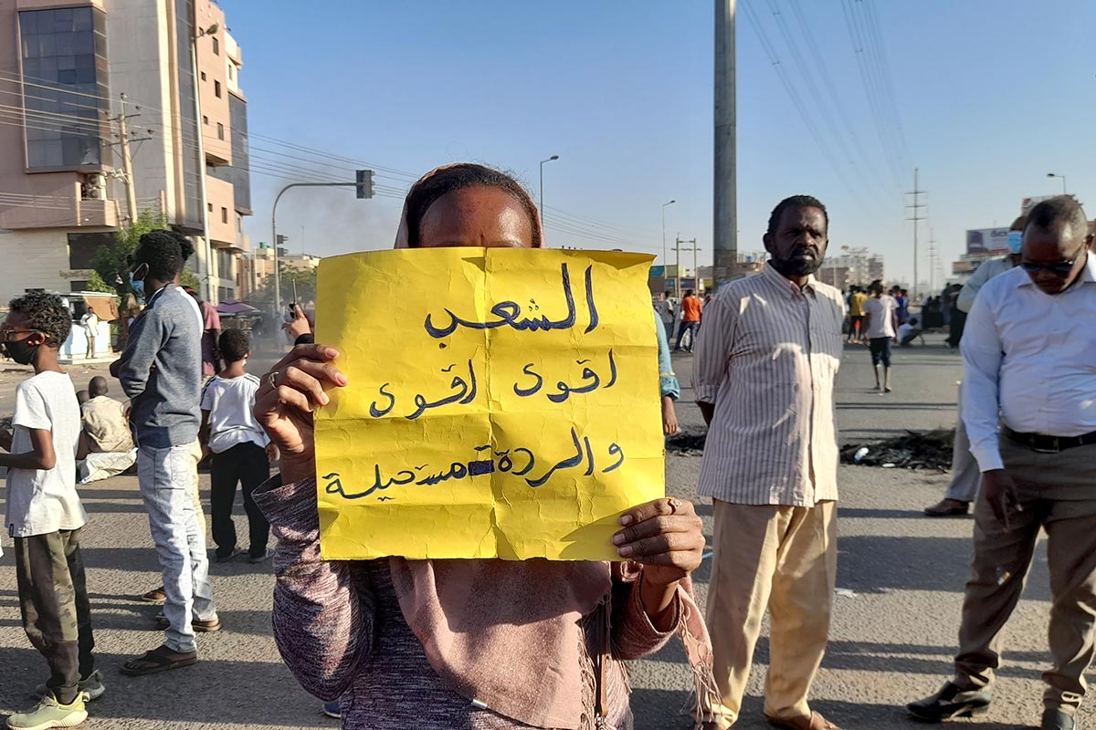 Un manifestant tient une pancarte sur laquelle il est écrit "Le peuple est le plus fort et tout retour en arrière impossible".