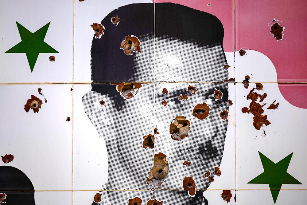 A portrait of Bashar al-Assad riddled with bullets, in the north-eastern outskirts of Damascus, the capital of Syria, a few weeks after his fall from power on 8 November 2024. Photo: © Sameer al-Doumy / AFP Portrait of Bashar al-Assad painted on a wall in Syria, showing bullet holes.