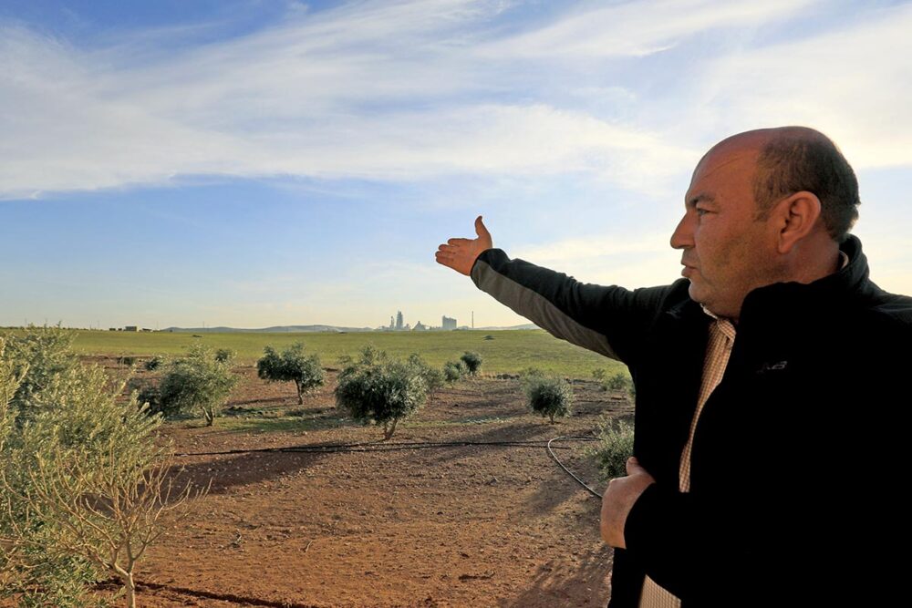 Procès Lafarge en France pour des crimes commis en Syrie, dont d'éventuels 'crimes contre l'humanité' qui feront peut-être l'objet d'un second procès. Photo : un ancien sous-traitant de Lafarge en Syrie montre (de loin) l'usine de Jalabiya où il a travaillé.