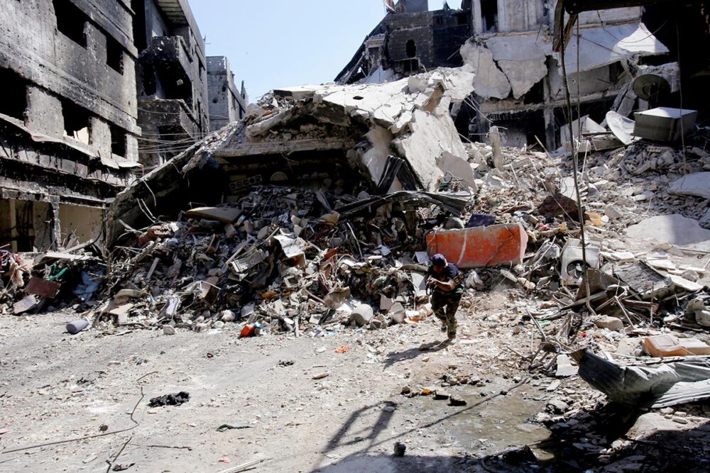 A fighter from the Popular Front for the Liberation of Palestine, allied with Syrian President Bashar al-Assad, photographed in the Yarmouk refugee camp on the outskirts of Damascus on 12 September 2013. Photo: © Anwar Amro / AFP In Syria, an armed fighter from the Popular Front for the Liberation of Palestine, allied with Syrian President Bashar al-Assad, crosses a street in the Yarmouk refugee camp.
