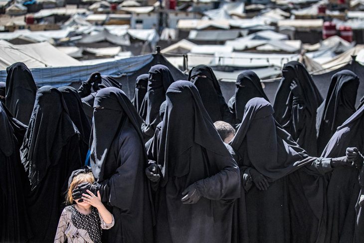Women all dressed in black and a child in a refugee camp