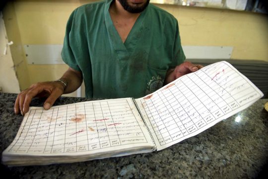 A doctor holds a bloodstained open book in a hospital