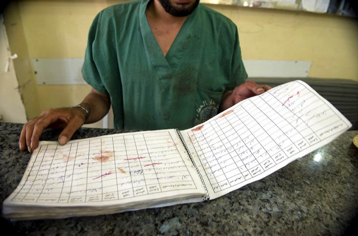 A doctor holds a bloodstained open book in a hospital