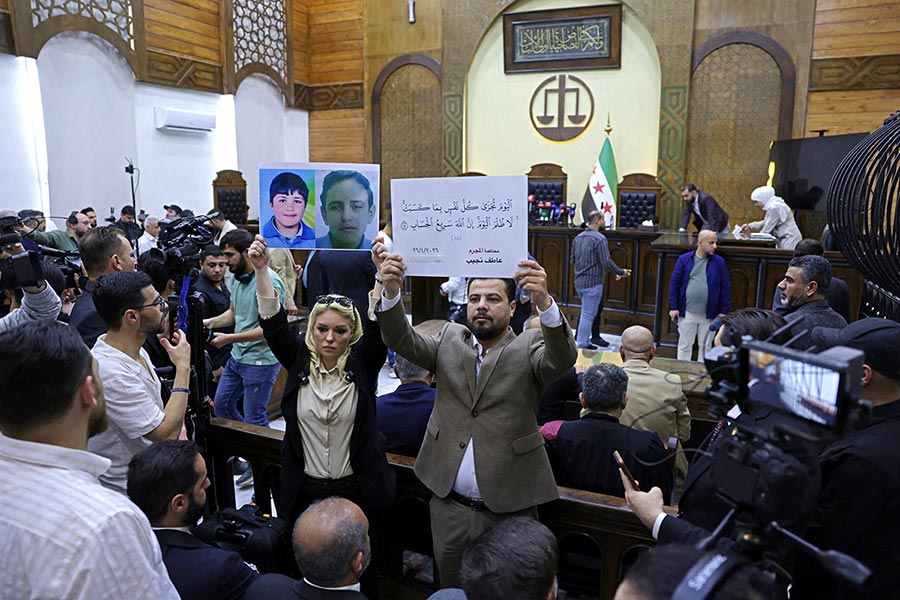 “This Day shall every person be recompensed for what he earned. No injustice (shall be done to anybody). Truly, Allah is Swift in reckoning”, tells a placard held by relatives of victims at the opening of the trial of Atef Najib in Syria.