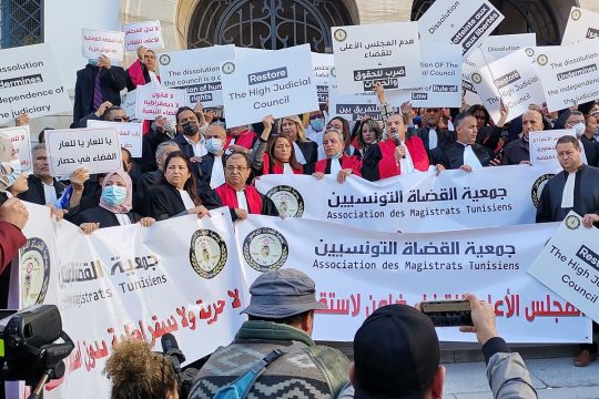 Magistrates and lawyers hold signs and banners that read 