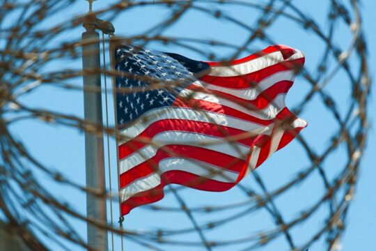 Guantanamo: a thorn in the side of the United States. The infamous US prison is regularly criticised for its illegal detentions and the torture practised there. Photo: an American flag flies in the sky, behind the prison’s barbed wire.