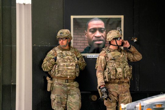 Two American soldiers in front of a portrait of George Floyd posted in the street