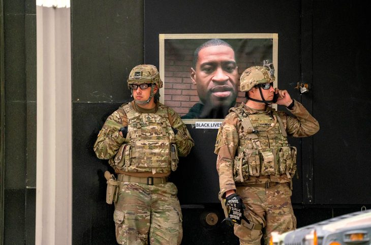 Two American soldiers in front of a portrait of George Floyd posted in the street
