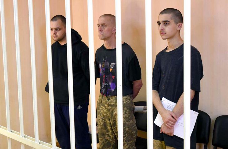 3 soldiers (Aiden Aslin, Shaun Pinner and Brahim Saadoun) stand behind bars