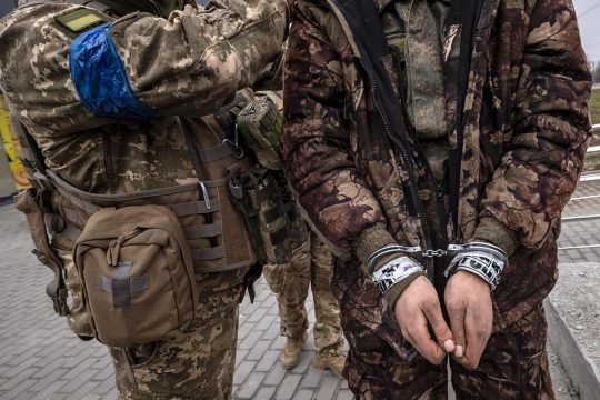 Украинский солдат сопровождает закованного в наручники российского солдата в Харькове, на севере Украины, 31 марта 2022 года, 36-й день российско-украинского конфликта.