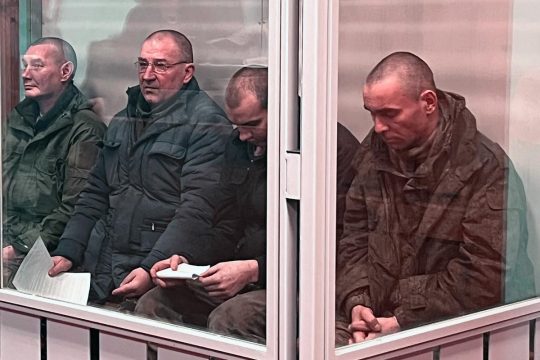 4 soldats russes en uniformes sont assis dans le box des accusés lors de leur procès pour torture en Ukraine.