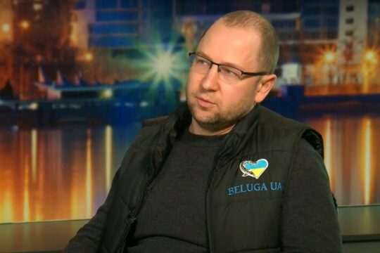 Artem Piskarev, lawyer for victims of war crimes in Ukraine. Photo (from a video interview): Piskarev wears a black jacket with a logo featuring a fish around a Ukrainian flag in the shape of a heart, above the inscription ‘Beluga UA’.