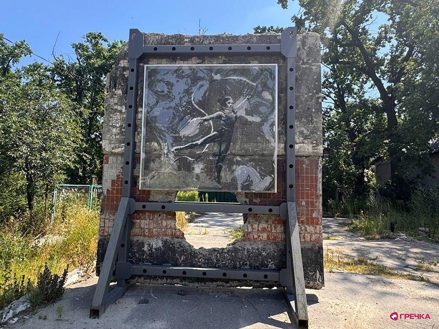 Une oeuvre du célèbre street artist Banksy est exposée à Irpin (Ukraine). Photo : une gymnaste est peinte sur un pan de mur isolé et protégé par du verre. En-dessous de la gymnaste, un gros trou dans le mur.