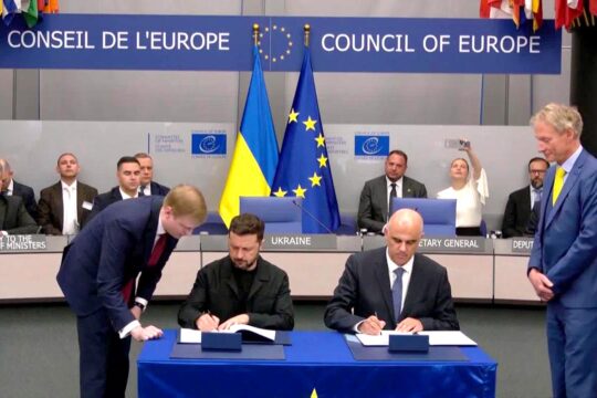 Volodymyr Zelensky signe un accord avec le Conseil de l'Europe sur la création du Tribunal spécial pour le crime d’agression contre l’Ukraine. Photo : Zelensky et Alain Berset (secrétaire général du Conseil de l'Europe) sont assis à une table et signent des documents. En arrière-plan : un drapeau de l'Ukraine et un autre de l'Europe.