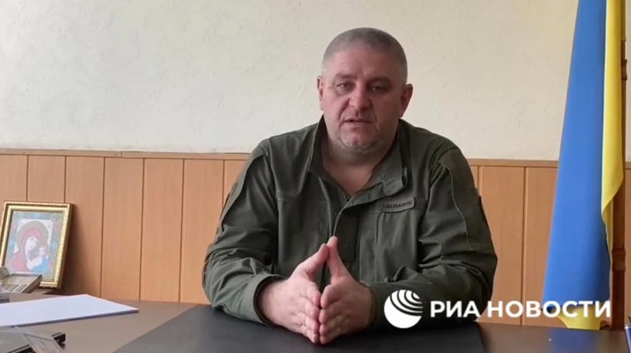 Screenshot from a video in which Ihor Huryakov states that he asked Russian forces to strengthen security at the detention centre he was in charge of in Kherson. A Ukrainian flag is placed behind him.