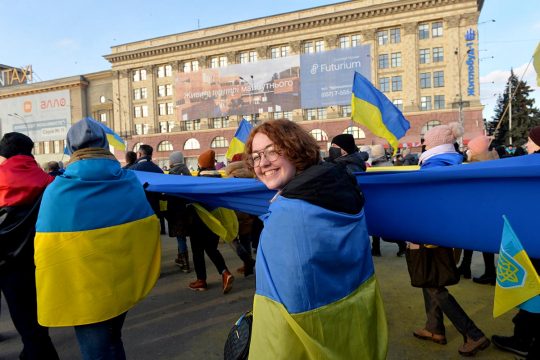 Protesters wrapped in Ukrainian flags march through the streets of central Kharkiv
